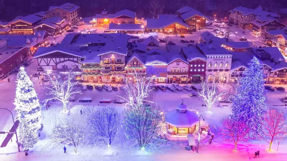 Leavenworth, Washington Aerial view of a snow-covered village at night with festive lights, decorated trees, and illuminated streets